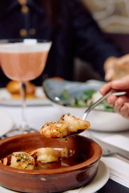 Sizzling prawns cooked in olive oil, garlic, and chili served in a terracotta dish.