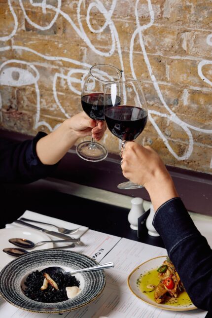 Two people toasting with glasses of red wine.