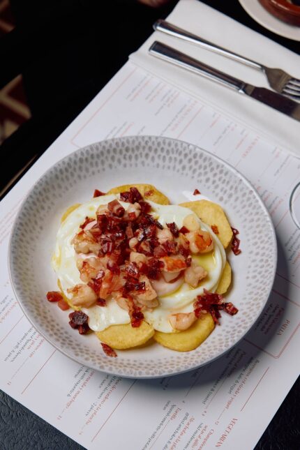A portion of patatas bravas topped with spicy tomato sauce and alioli.