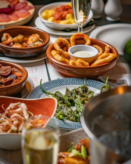 An assortment of classic Spanish sharing plates including patatas bravas and crispy calamari.